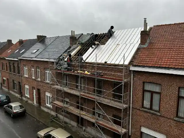 Rijwoning met stelling tijdens het isoleren van het dak langs buiten